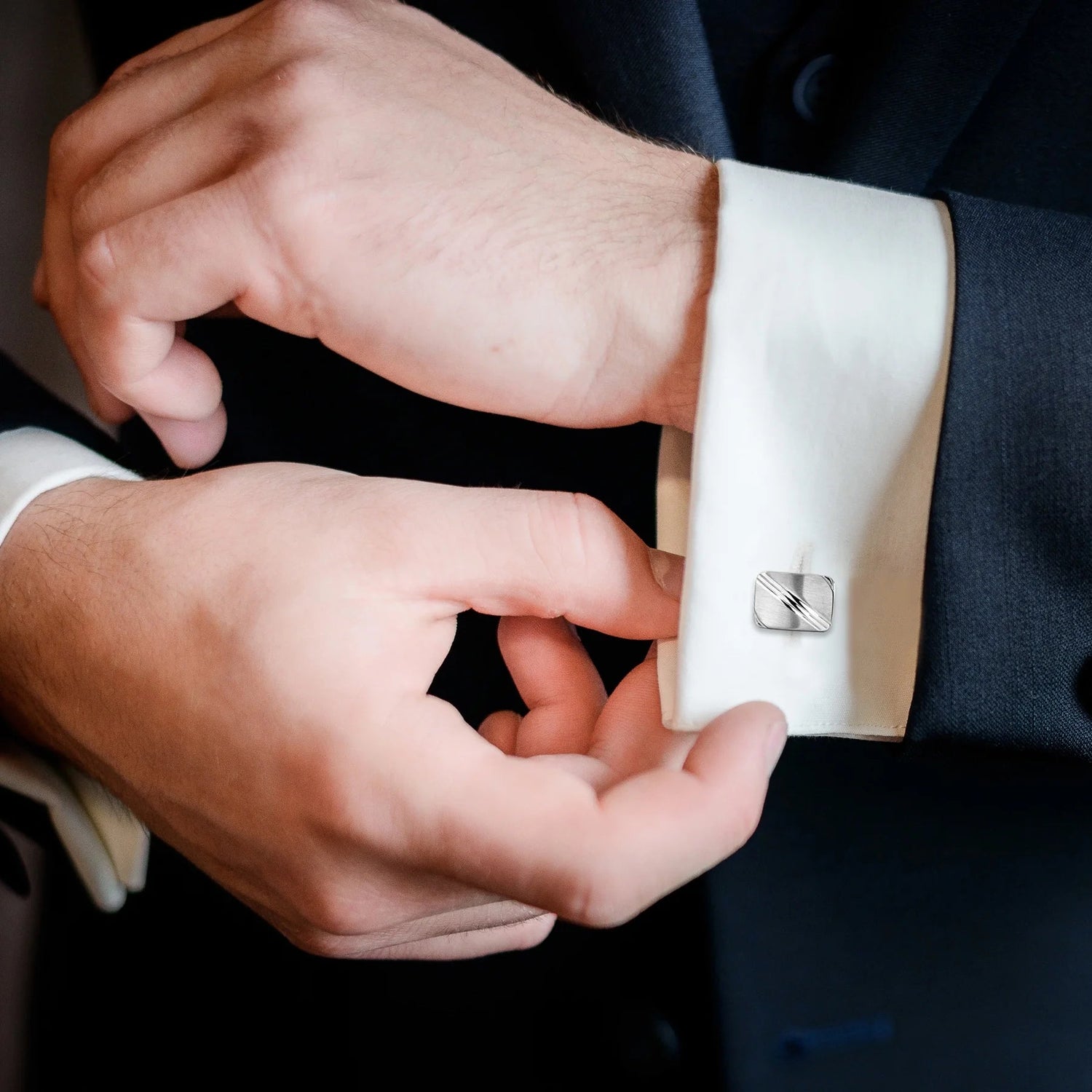 close up picture of a man adjusting suit stainless steel cufflinks low res