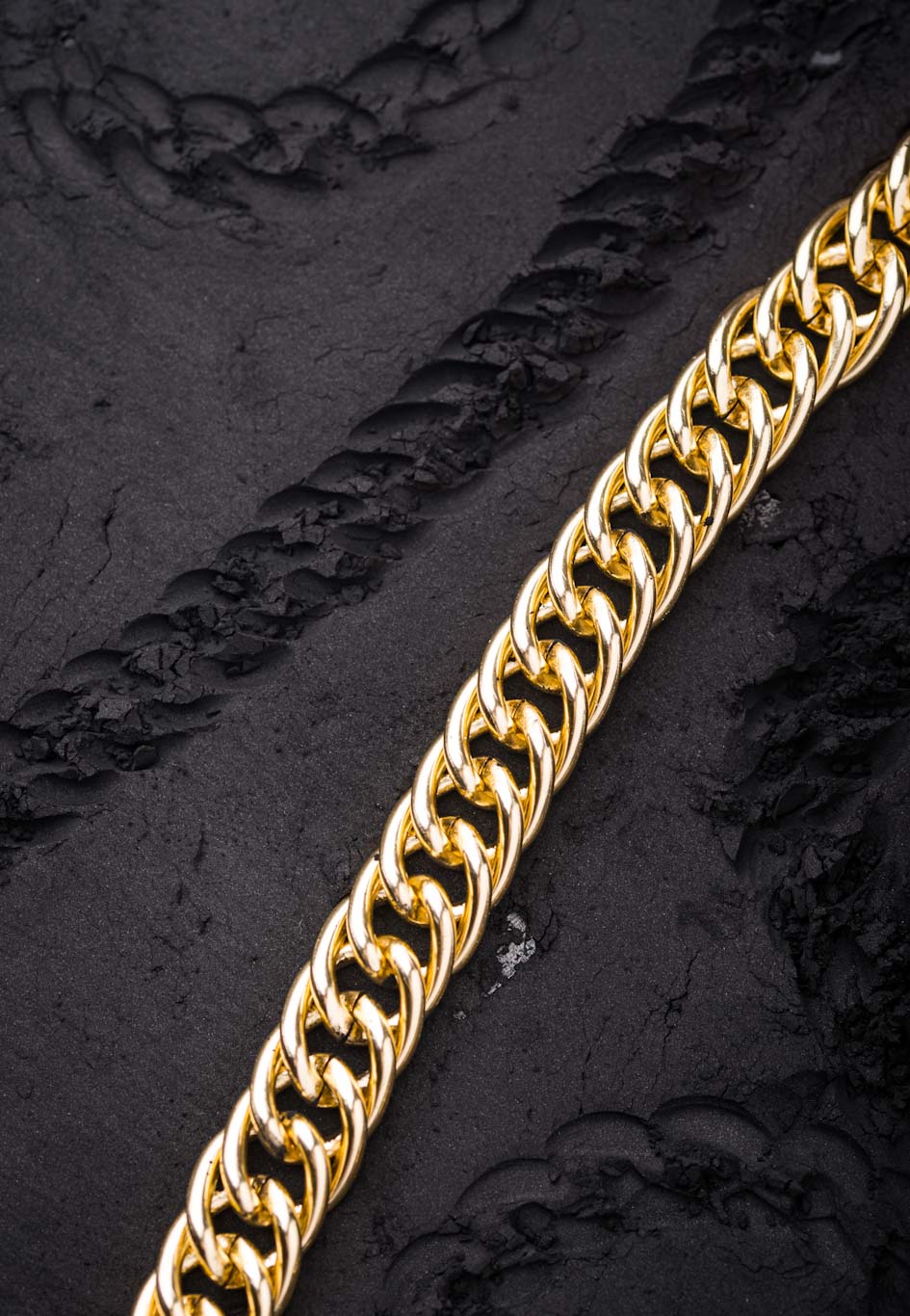 top down picture of a gold cuban ling chain, and a black cuban link chain on  a black background