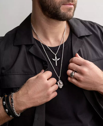 pictured is a rugged white man styling Marc Anthony Men's sterling silver black diamond angel wing cross pendant