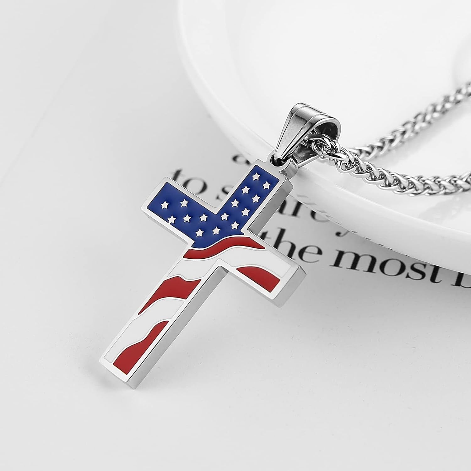 close up picture from the right of a stainless steel high-polished with red white and blue enamel on the edge of a plate with bible scripture in the background