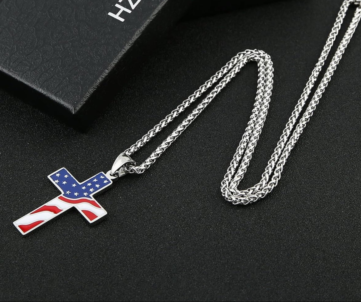 Top down picture of a full american flag cross necklace with box chain laying on a black background